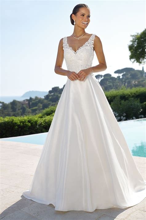 A Woman In A White Wedding Dress Standing Next To A Pool And Smiling At