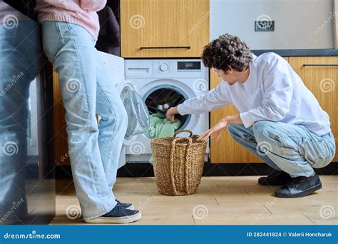 Young Guy At Home Using Washing Machine With Basket Of Dirty Things