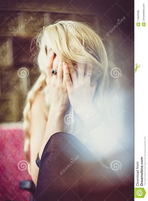 Femme Blonde S Asseyante Pleurant Et Cachant Son Visage Photo Stock