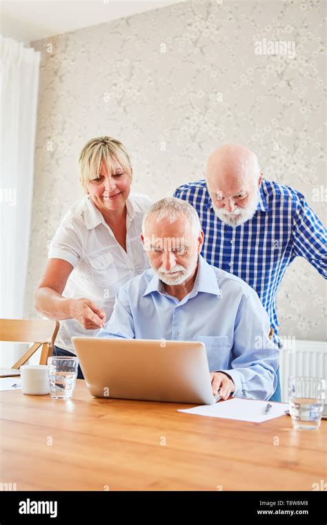 Caregiver Cares For Two Seniors In The Computer Course With The Laptop