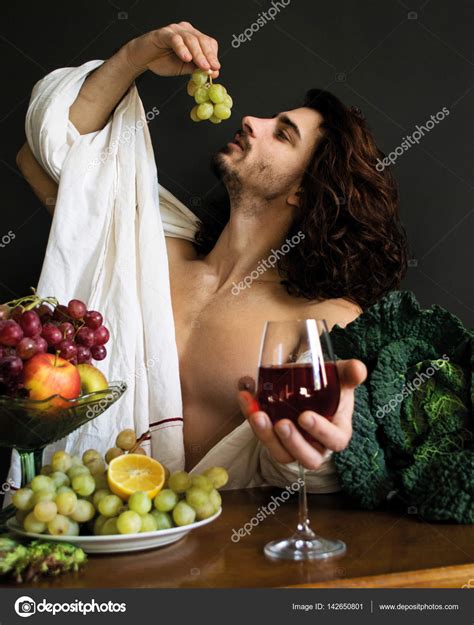 Photo Half Naked Curly Guy At A Table With Fruits And Wine Eating