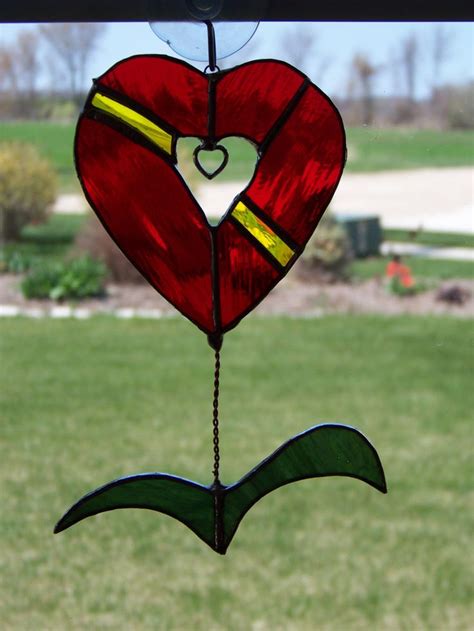 A Stained Glass Heart Hanging From A Window In Front Of A Green Lawn