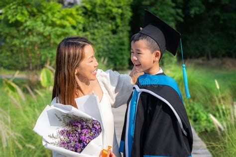 Asian Preschool Boy In Graduate Uniform Sit With His Mother Stock Photo