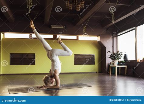 A Woman Practicing Yoga Performs Shirshasana Exercise With Bent Leg