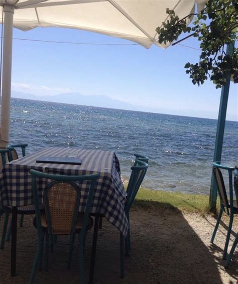 An Outdoor Dining Area Overlooking The Ocean With Tables And Chairs Set