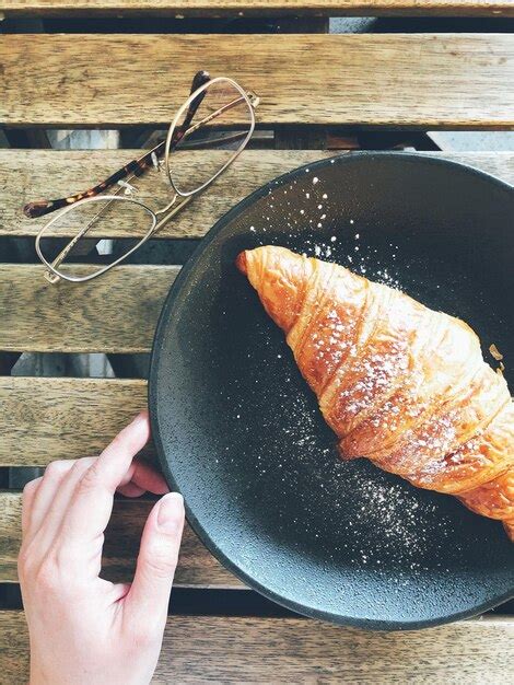 Premium Photo Close Up Of Hand And Croissant On Table