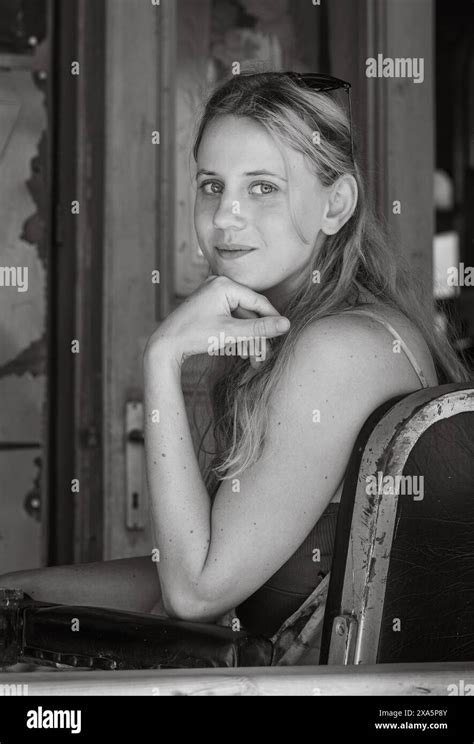 Monochrome Portrait Of A Blonde Woman Sitting In A Retro Chair Chin Resting On Hand Stock Photo