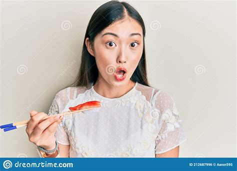 Young Chinese Woman Eating Prawn Sushi Using Chopsticks Scared And