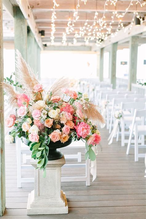 An Arrangement Of Flowers In A Vase On A Pedestal At The End Of A