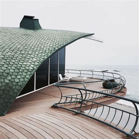 The Roof Of A Building With Curved Metal Railings Next To The Ocean On