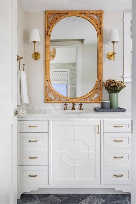 Thomas O Brien Bryant Sconces Flank An Orange Rattan Mirror Hung Over A