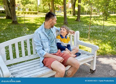 Father With Son Sitting On Park Bench And Talking Stock Image Image