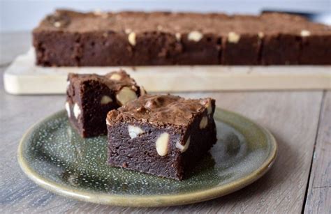 Two Pieces Of Chocolate Brownie On A Green Plate Next To A Knife And Fork