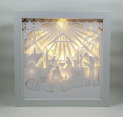 A Paper Cut Nativity Scene With The Birth Of Jesus And Baby Jesus In White