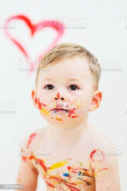 Child Boy Smeared With Multicolored Paints Hands Face And Body Sitting