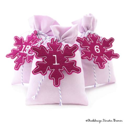 Three Small Pink Bags With Numbers And Snowflakes On The Top Tied Together