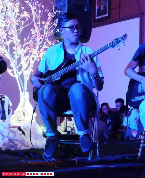 A Man Sitting On Top Of A Chair While Holding A Guitar In Front Of Him