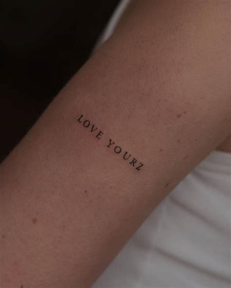 "Love yourz" lettering tattoo located on the upper arm.