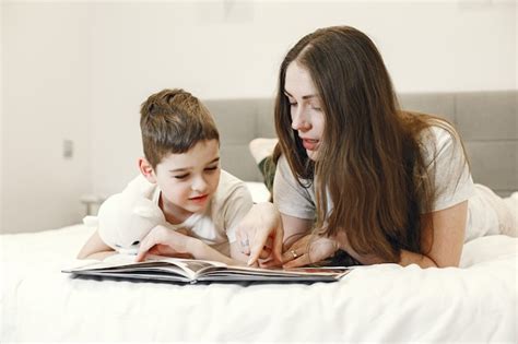 Mãe e filho deitado na cama lendo um livro Foto Grátis