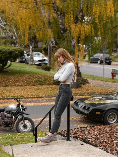 Woman In White Long Sleeve Shirt And Black Pants Standing Beside Black Sports Bike · Free Stock