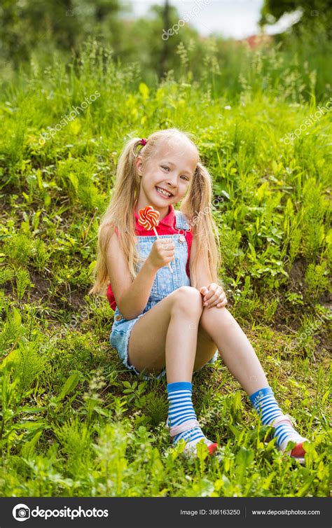 Petite fille blonde aux cheveux longs et bonbons sur un bâton Photo