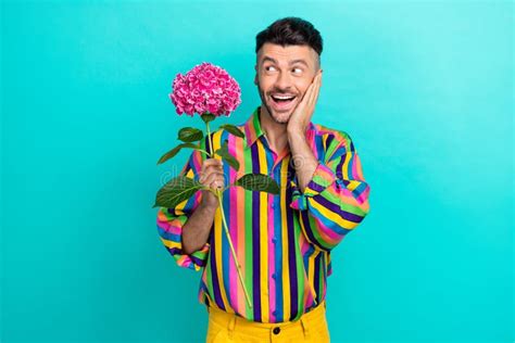 Photo Of Cheerful Funky Man Hand Touch Cheek Hold Flower Toothy Smile Look Empty Space Isolated