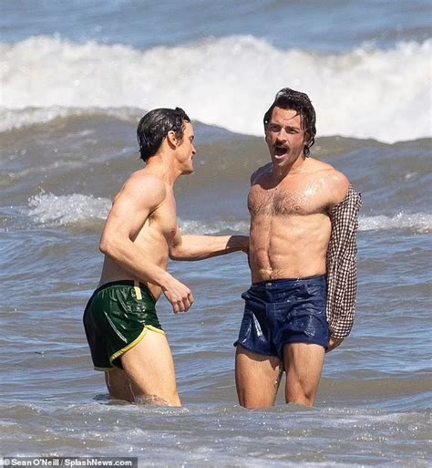 Two Men Standing In The Ocean With One Holding His Hand Out To Another