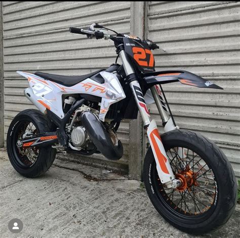 An Orange And White Dirt Bike Parked In Front Of A Garage Door With