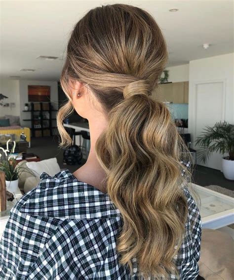 A Woman With Long Wavy Hair In A Ponytail Is Seen From The Back View