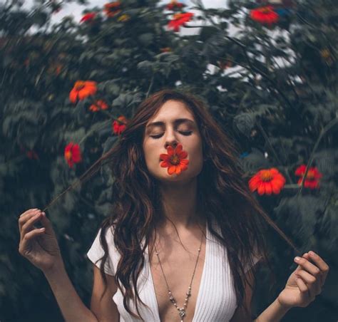 A Woman With Flowers On Her Face Blowing In The Wind Surrounded By Red