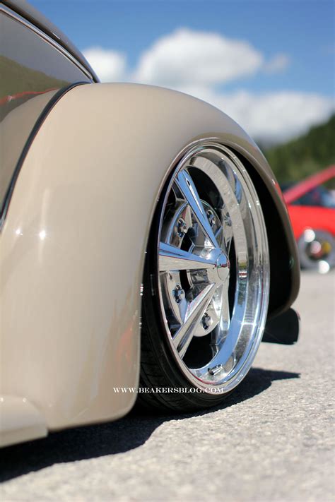 The Front End Of A Classic Car With Chrome Rims And Spokes On It