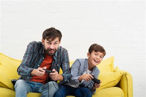 Père Et Fils Assis Sur Un Canapé Et Jouant Sur Console Photo Gratuite