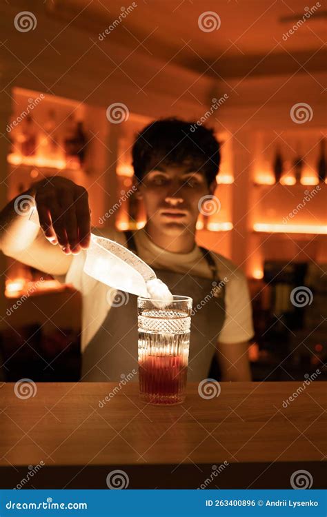 Professional Bartender Putting Ice Cubes To The Cocktail Glass With