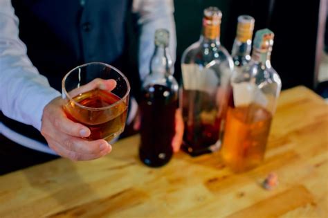 Premium Photo Midsection Of Bartender Holding Whiskey In Glass At Bar