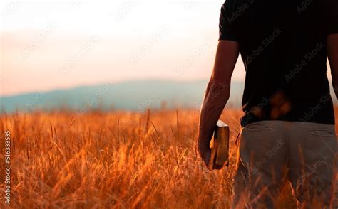 Human Praying On The Holy Bible In A Field During Beautiful Sunset