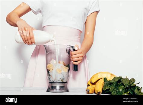 Young Woman Making Spinach Banana Smoothie On White Background She