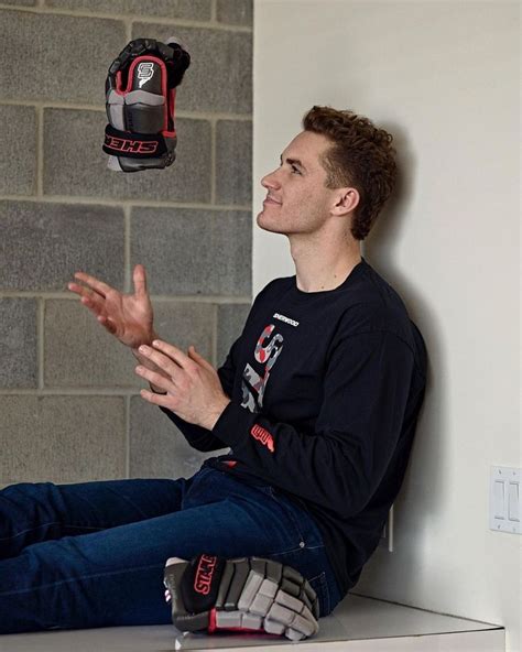 A Man Sitting On Top Of A White Counter Next To A Red And Black Glove