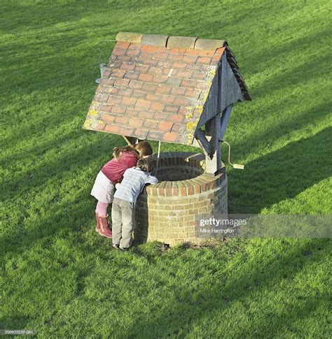 Boy And Girl Looking Down Well In Garden Elevated View High Res Stock