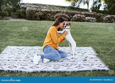 Woman Having Fun With Jack Russell Dog In Park Sitting On Blanket