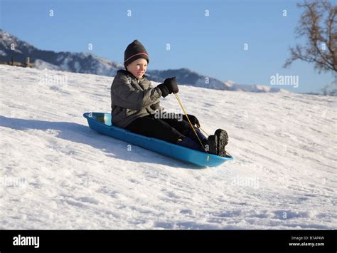 Young Boy Sledding Down A Snowy Hill On A Blue Sled Stock Photo Alamy