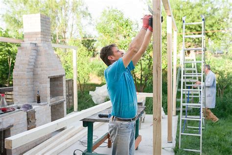 Man Making Measurements On Wooden Pylon Of Wooden Built Structure By