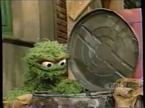 the sesame street character is sitting in front of a trash can