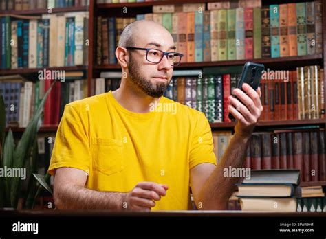 Communication A Bald Bearded Man With Glasses Uses A Smartphone In