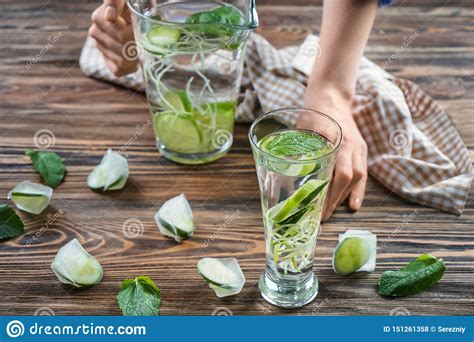 Mujer Con El Jarro De Agua Fresca Del Pepino Que Alcanza Para El Vidrio