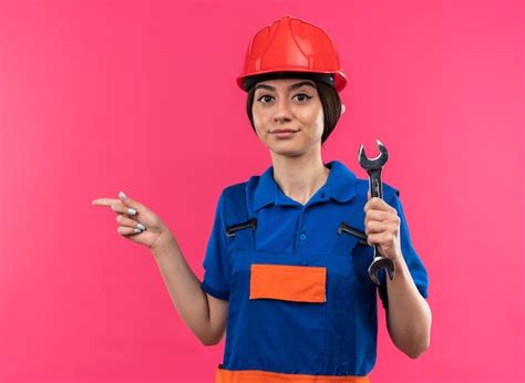 Contento mirando a la cámara joven constructor mujer en uniforme