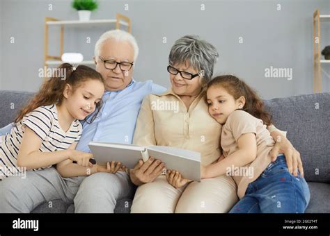 Happy Grandma Grandpa And Grandkids Reading A Book Or Looking Through