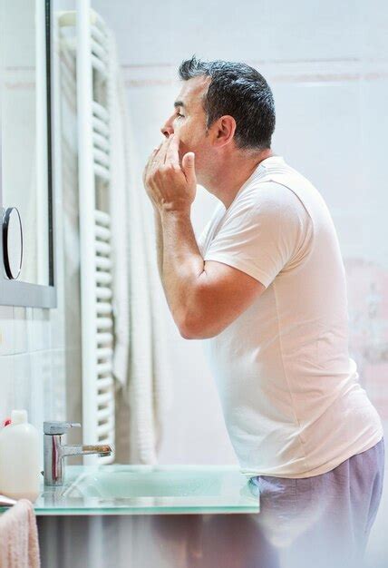 Premium Photo Side View Of Mature Man Wearing Domestic Clothes Stroking Face With Cream During