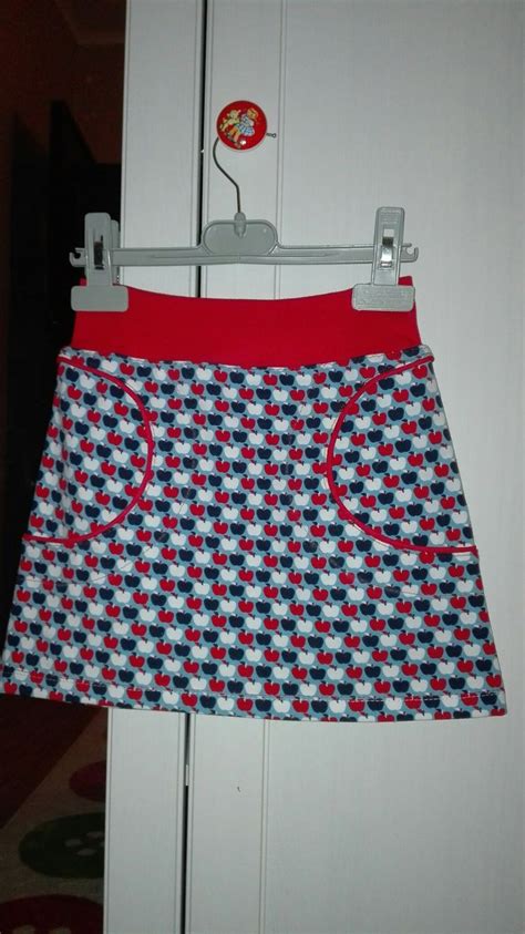 A Red And Blue Skirt Hanging On A White Door With A Button In The Middle