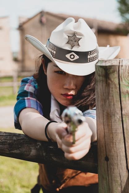 Premium Photo Portrait Of Cowgirl Holding Gun While Standing At Ranch