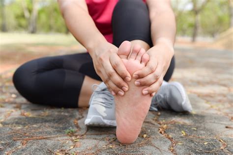 Mujer Del Primer Que Da Masajes A Su Dolor Del Pie En El Piso Mientras